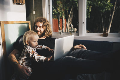 Rear view of man using laptop while sitting at home