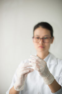 Close-up of doctor holding syringe against gray background