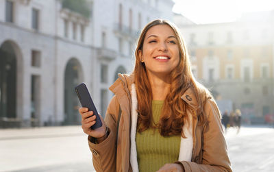 Young smiling woman using mobile phone outdoors