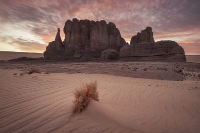 Rock formation on beach against sky during sunset