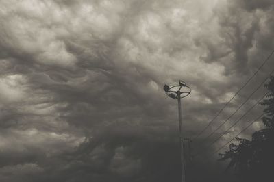 Low angle view of electricity pylon against storm clouds