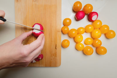 Close-up of female hands cutting fresh radish on cutting board at home kitchen