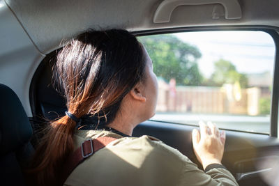 Young woman looking through window in car