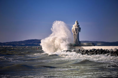 Waves splashing in sea against clear sky