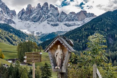 Virgin mary by tree against mountain