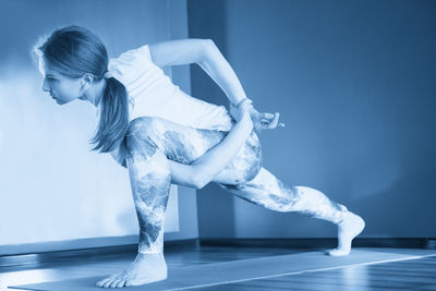 Side view of woman exercising against clear sky