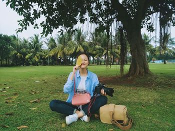 Young woman sitting on tree at park