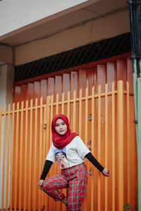 Portrait of young woman standing against building