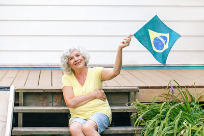 Proud citizen celebrating independence day of brazil. happy old woman holding brazilian flag outdoor