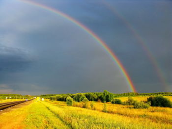 Scenic view of rainbow over field against sky