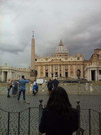 Rear view of people at temple against cloudy sky