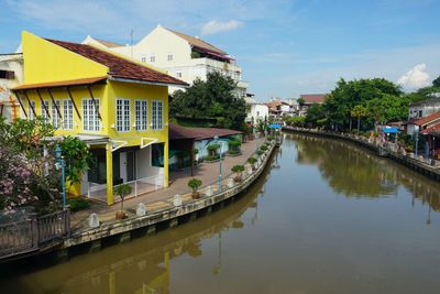 Canal amidst buildings in city against sky