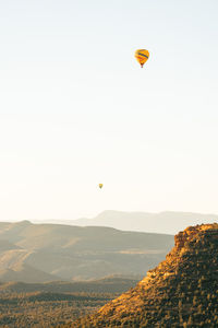 Two hot air balloons high and low taking flight in early morning in sedona arizona.