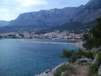 Scenic view of sea by townscape against sky