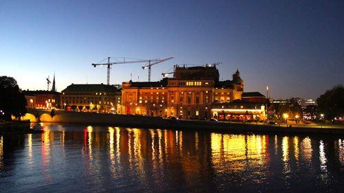 River by illuminated city against clear sky at night