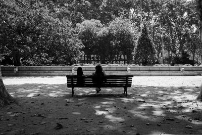 Rear view of woman sitting on bench at park