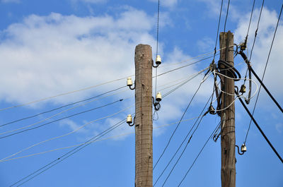 Low angle view of telephone poles against blue sky