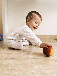 Portrait of cute baby boy sitting on hardwood floor at home