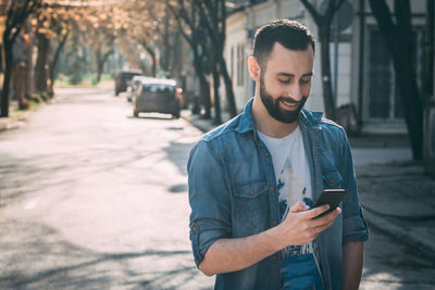 Young man using phone while standing on street