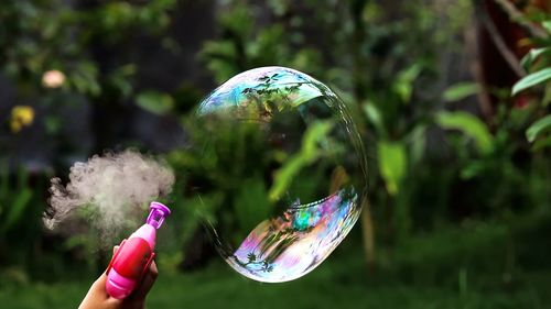 Cropped hand of person blowing bubble outdoors