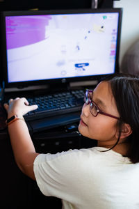 A young gamer girl at home in a room playing with friends on the networks in computer video games.