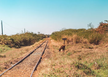 Railroad tracks on field against clear sky