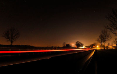 Light trails on road against sky at night