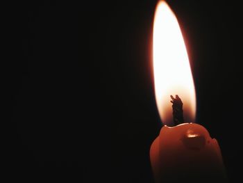 Close-up of lit candle in darkroom