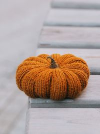 Knitted orange pumpkin on a wooden table.