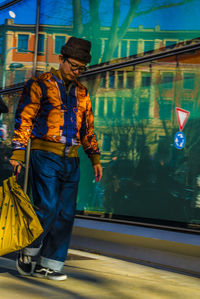 Man holding umbrella while standing by bridge