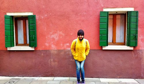 Full length of man standing against yellow building