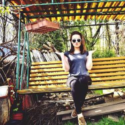 Portrait of young woman standing on tree trunk