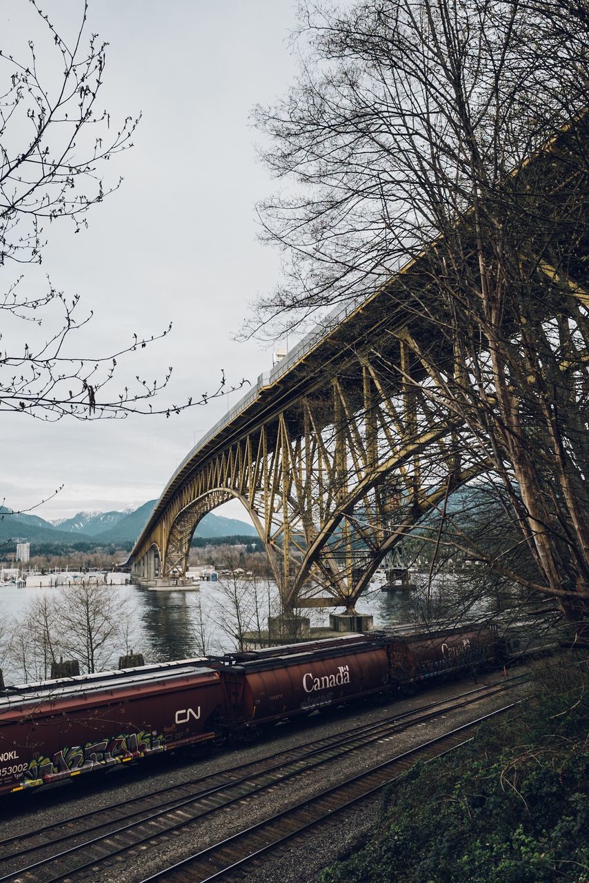 built structure, architecture, connection, bridge - man made structure, transportation, tree, river, water, clear sky, sky, bridge, engineering, arch, railroad track, building exterior, arch bridge, travel destinations, city, travel, bare tree