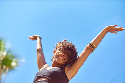 Low angle view of woman against clear blue sky