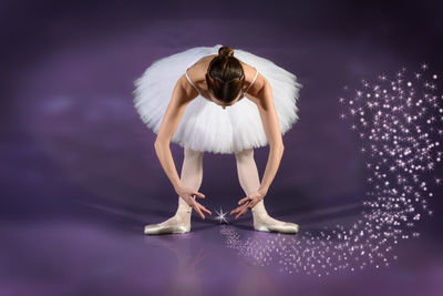 Young woman dancing against purple background