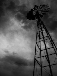 Low angle view of electricity pylon against cloudy sky