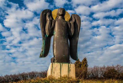 Low angle view of statue on field against sky