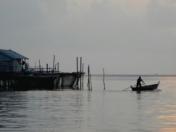 Gondolier on boat in sea during sunset