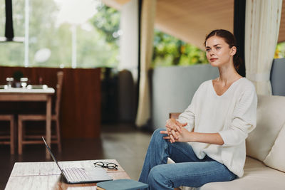 Portrait of young woman reading book at home