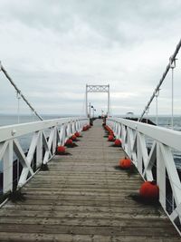 Footbridge over sea against sky