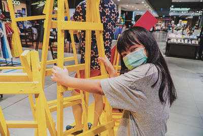 Portrait of smiling cute girl wearing mask standing at supermarket