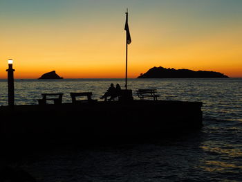 Silhouette people on beach against sky during sunset