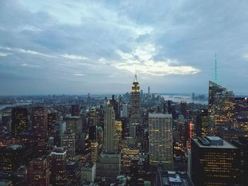 Empire state building amidst cityscape during sunset