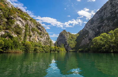 Scenic view of lake by mountains against sky