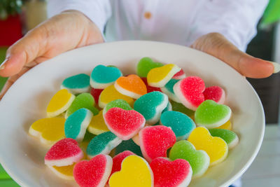 Midsection of woman carrying colorful candies in plate