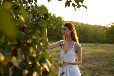 Full length of woman standing by tree