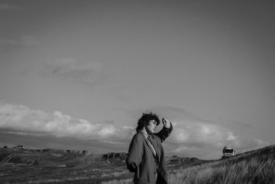 Side view of woman standing on field against sky