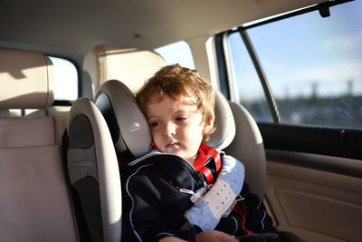 Tired boy sitting in car while traveling