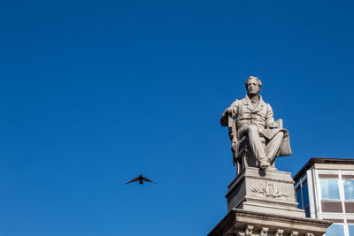 A dove passes flying near the statue in piazza stesicoro