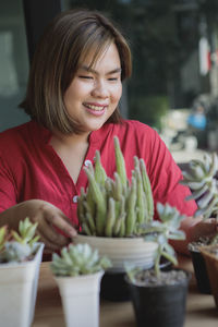 Smiling woman sitting by succulent plant on table